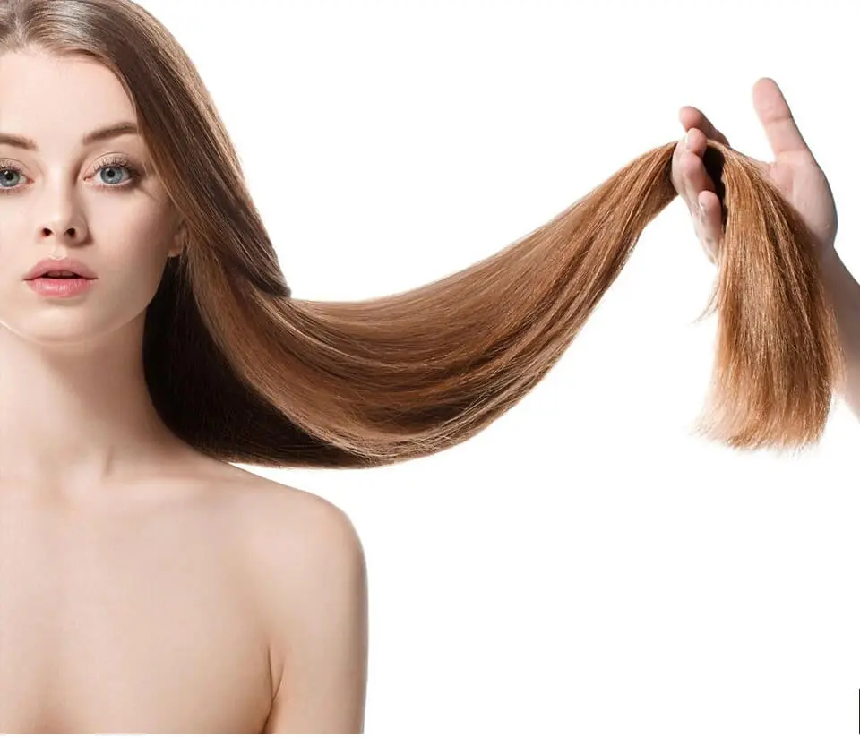 A woman with long hair is holding her hair.