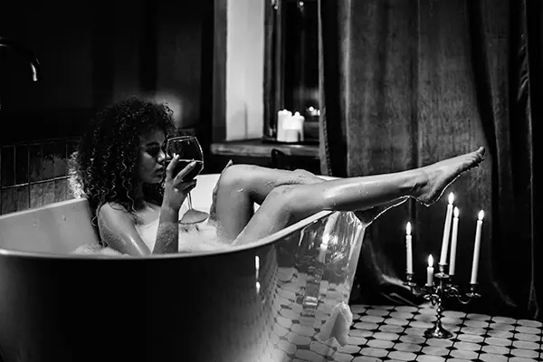 Women sitting in bath tub holding glass